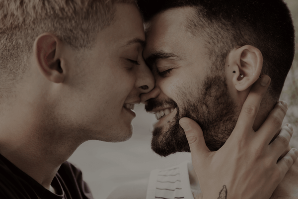 Two men facing each other smiling as if to kiss