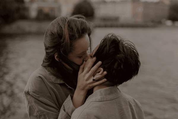 Un couple qui s’embrasse, le vent soufflant dans leurs cheveux.